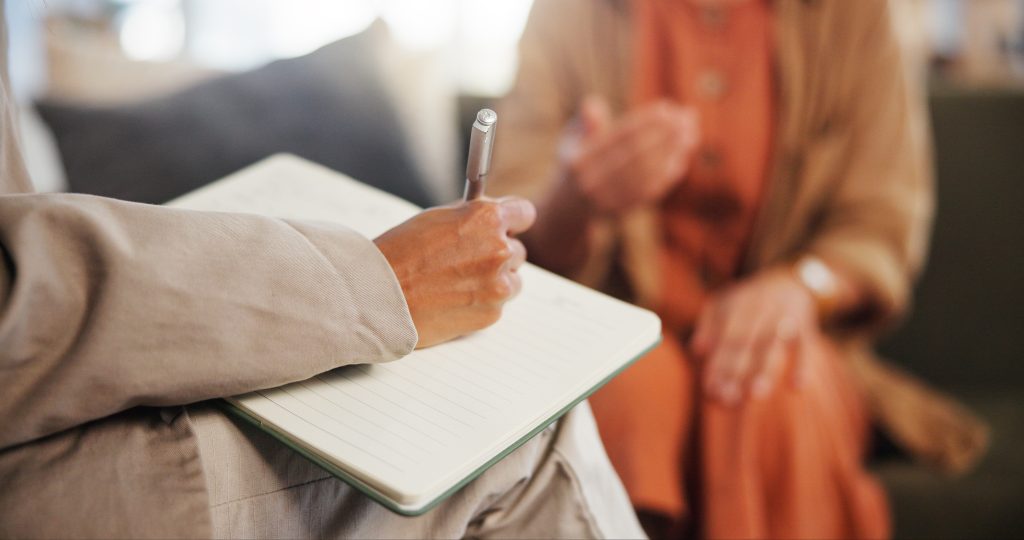 book-counseling-and-hand-of-therapist-writing-notes